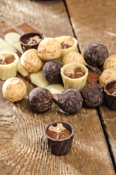 Chocolates y chocolate en una canasta sobre una mesa de madera —  Fotos de Stock