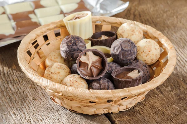 Chocolates and chocolate in a basket on a wooden table — Stock Photo, Image