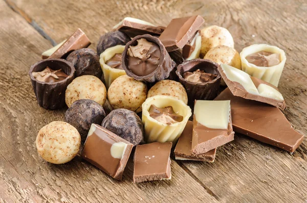 Chocolates y chocolate en una canasta sobre una mesa de madera — Foto de Stock