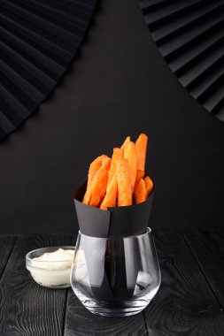 Siyah arka planda bir bardakta patates kızartması..