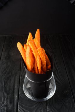 Siyah arka planda bir bardakta patates kızartması..