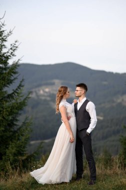 Mutlu şık gelin ve damat yaz güneşli bir günde dağlarda koşup eğleniyor.
