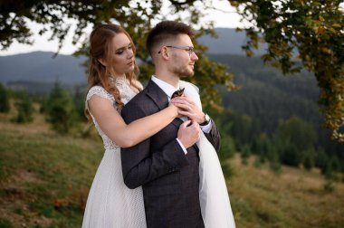 Mutlu şık gelin ve damat yaz güneşli bir günde dağlarda koşup eğleniyor.