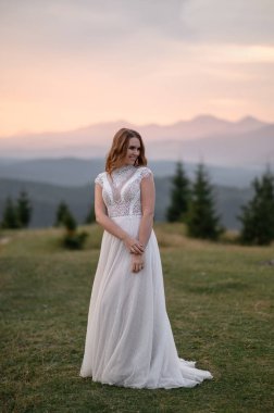 Dağların arkasında beyaz bir gelinlik içinde güzel bir gelin..