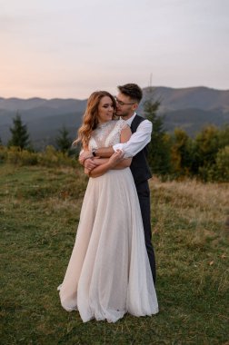 Mutlu şık gelin ve damat yaz güneşli bir günde dağlarda koşup eğleniyor.