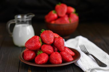 Kırsal ahşap masada bir kase kırmızı sulu çilek. Sağlıklı ve diyet atıştırmalık.