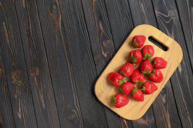 Kırsal ahşap bir masada kırmızı sulu çilekler. Sağlıklı ve beslenme atıştırmalıkları kavramı.
