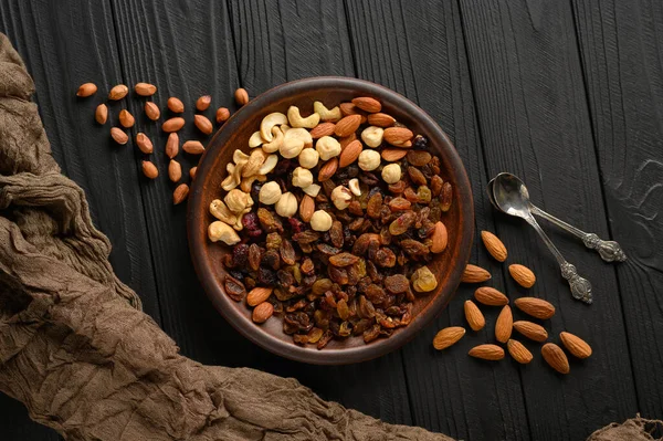 Hazelnuts, cashews, raisins, almonds, peanuts, walnuts on a wooden black background