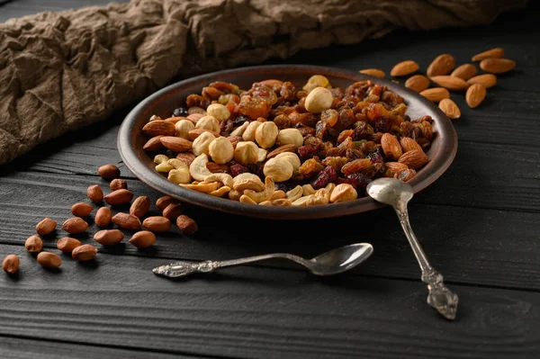 Hazelnuts, cashews, raisins, almonds, peanuts, walnuts on a wooden black background