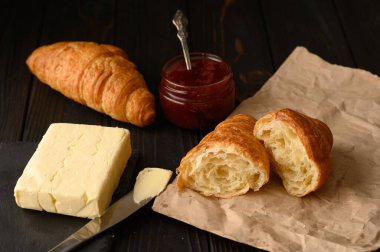 Böğürtlen reçelli ve tereyağlı taze kruvasan, koyu ahşap arka plan, seçici odak