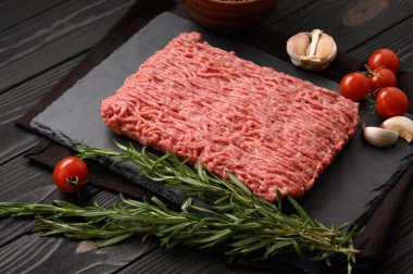 Tahta kesme tahtasındaki taze çiğ et ya da tavuk eti kekik, baharat ve sarımsaklı. Kırsal ahşap arka plan. Üst Manzara. Boşluğu kopyala.