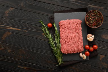 Tahta kesme tahtasındaki taze çiğ et ya da tavuk eti kekik, baharat ve sarımsaklı. Kırsal ahşap arka plan. Üst Manzara. Boşluğu kopyala.