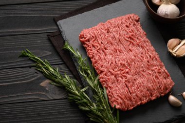 Tahta kesme tahtasındaki taze çiğ et ya da tavuk eti kekik, baharat ve sarımsaklı. Kırsal ahşap arka plan. Üst Manzara. Boşluğu kopyala.