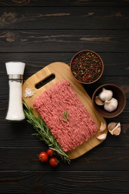 Tahta kesme tahtasındaki taze çiğ et ya da tavuk eti kekik, baharat ve sarımsaklı. Kırsal ahşap arka plan. Üst Manzara. Boşluğu kopyala.