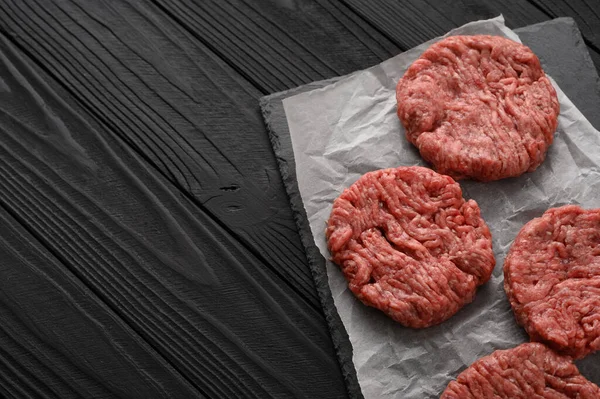 Raw Ground beef meat Burger steak cutlets on dark wooden background.
