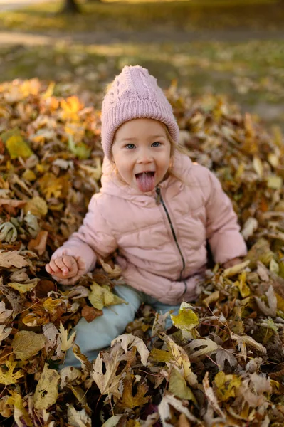 Uma Menina Brinca Uma Pilha Folhagem Outono — Fotografia de Stock