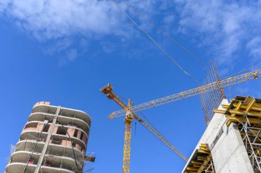 Mavi gökyüzüne karşı vinç ve inşaat alanı