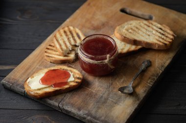 Toast bread with homemade strawberry jam and on rustic table with butter for breakfast or brunch.