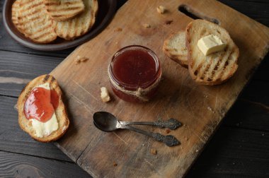 Toast bread with homemade strawberry jam and on rustic table with butter for breakfast or brunch.