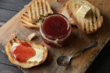 Toast bread with homemade strawberry jam and on rustic table with butter for breakfast or brunch.