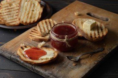 Toast bread with homemade strawberry jam and on rustic table with butter for breakfast or brunch.