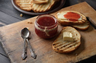 Toast bread with homemade strawberry jam and on rustic table with butter for breakfast or brunch.
