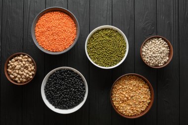 Koyu ahşap bir masa üzerinde çeşitli ham baklagiller.