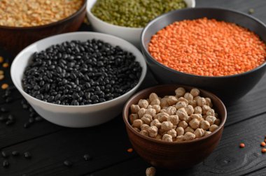 Koyu ahşap bir masa üzerinde çeşitli ham baklagiller.