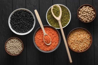 Koyu ahşap bir masa üzerinde çeşitli ham baklagiller.