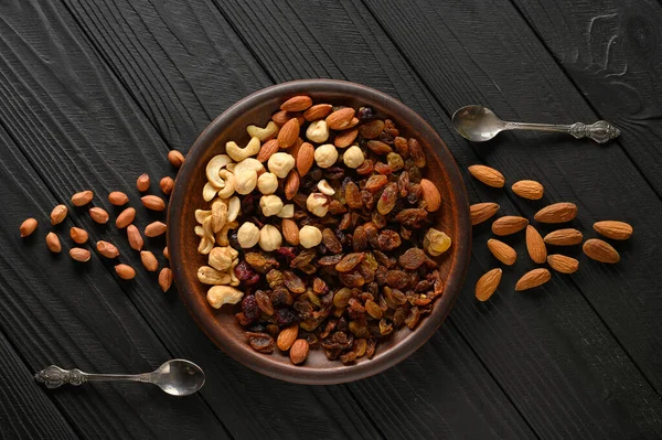 Hazelnuts, cashews, raisins, almonds, peanuts, walnuts on a wooden black background