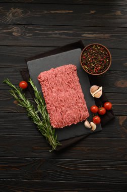 Tahta kesme tahtasındaki taze çiğ et ya da tavuk eti kekik, baharat ve sarımsaklı. Kırsal ahşap arka plan. Üst Manzara. Boşluğu kopyala.