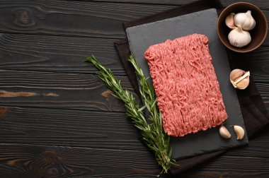 Tahta kesme tahtasındaki taze çiğ et ya da tavuk eti kekik, baharat ve sarımsaklı. Kırsal ahşap arka plan. Üst Manzara. Boşluğu kopyala.
