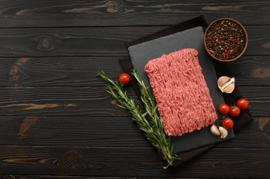 Tahta kesme tahtasındaki taze çiğ et ya da tavuk eti kekik, baharat ve sarımsaklı. Kırsal ahşap arka plan. Üst Manzara. Boşluğu kopyala.
