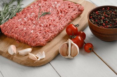 Tahta kesme tahtasındaki taze çiğ et ya da tavuk eti kekik, baharat ve sarımsaklı. Beyaz ahşap arka plan. Üst Manzara. Boşluğu kopyala.