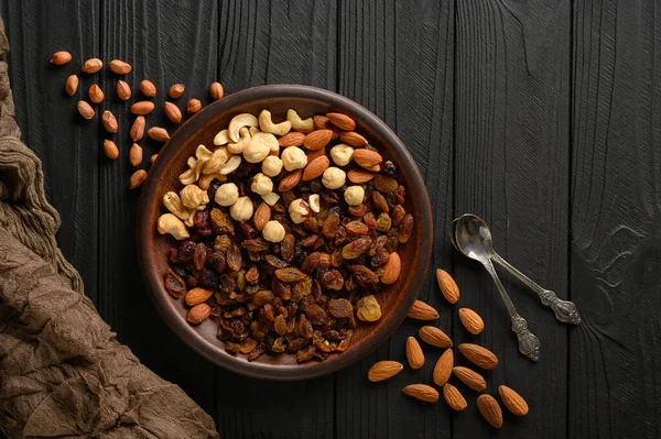 Hazelnuts, cashews, raisins, almonds, peanuts, walnuts on a wooden black background