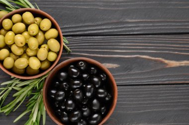 Koyu ahşap bir arka planda siyah ve yeşil zeytinler.