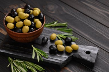 Koyu ahşap bir arka planda siyah ve yeşil zeytinler.