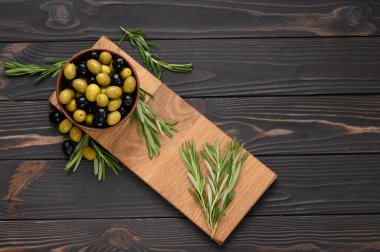 Koyu ahşap bir arka planda siyah ve yeşil zeytinler.