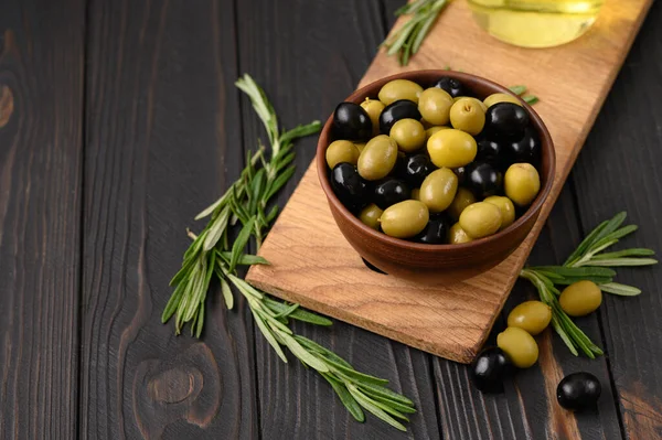 Black and green olives on a dark wooden rustic background.