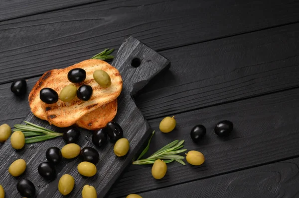 Black and green olives on a dark wooden black background.