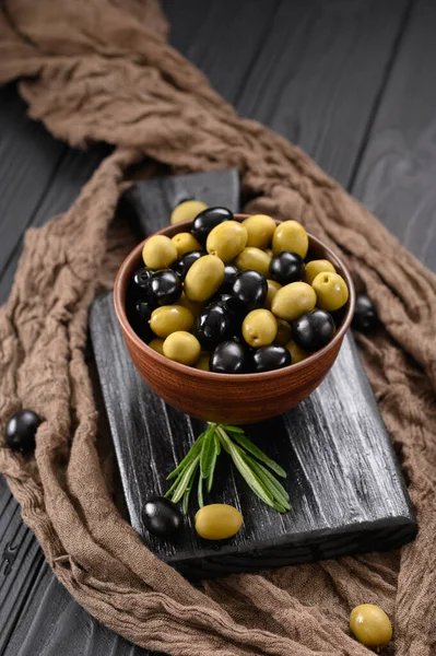 Black and green olives on a dark wooden black background.