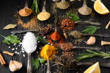 Koyu ahşap arka planda yemek pişirmek için çeşitli otlar ve baharatlar.