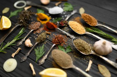 Koyu ahşap arka planda yemek pişirmek için çeşitli otlar ve baharatlar.