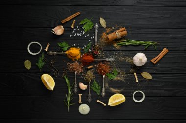 Koyu ahşap arka planda yemek pişirmek için çeşitli otlar ve baharatlar.