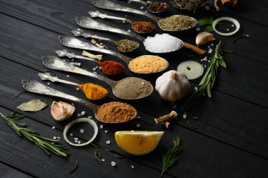 Koyu ahşap arka planda yemek pişirmek için çeşitli otlar ve baharatlar.