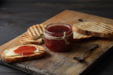 Toast bread with homemade strawberry jam and on rustic table with butter for breakfast or brunch.
