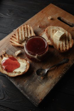 Toast bread with homemade strawberry jam and on rustic table with butter for breakfast or brunch.