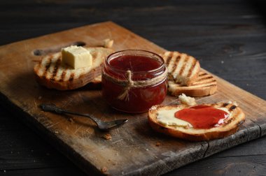 Toast bread with homemade strawberry jam and on rustic table with butter for breakfast or brunch.