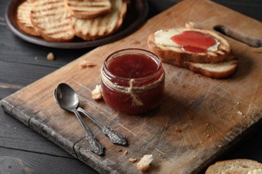 Toast bread with homemade strawberry jam and on rustic table with butter for breakfast or brunch.