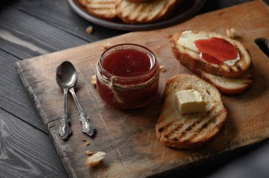 Toast bread with homemade strawberry jam and on rustic table with butter for breakfast or brunch.